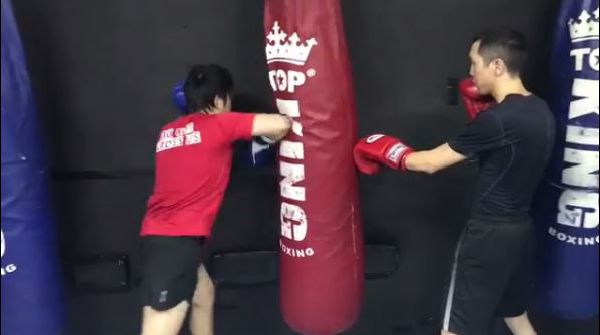 Muay Thai Singapore West students practicing Muay Thai elbowing techniques on boxing bags