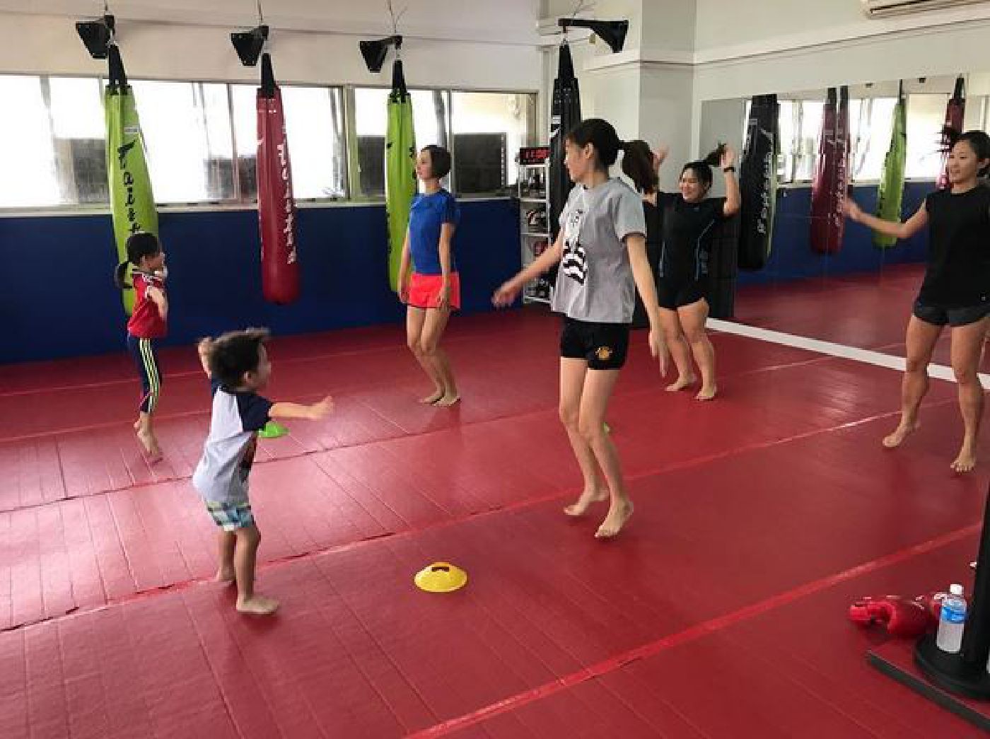 Muay Thai kids and their parents doing jumping jacks together
