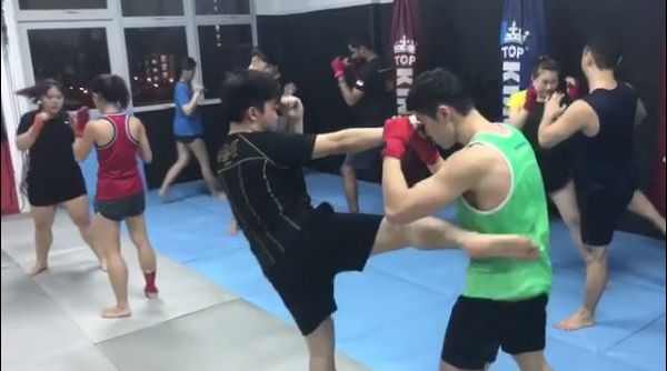 Muay Thai Singapore West students practicing roundhouse kicks